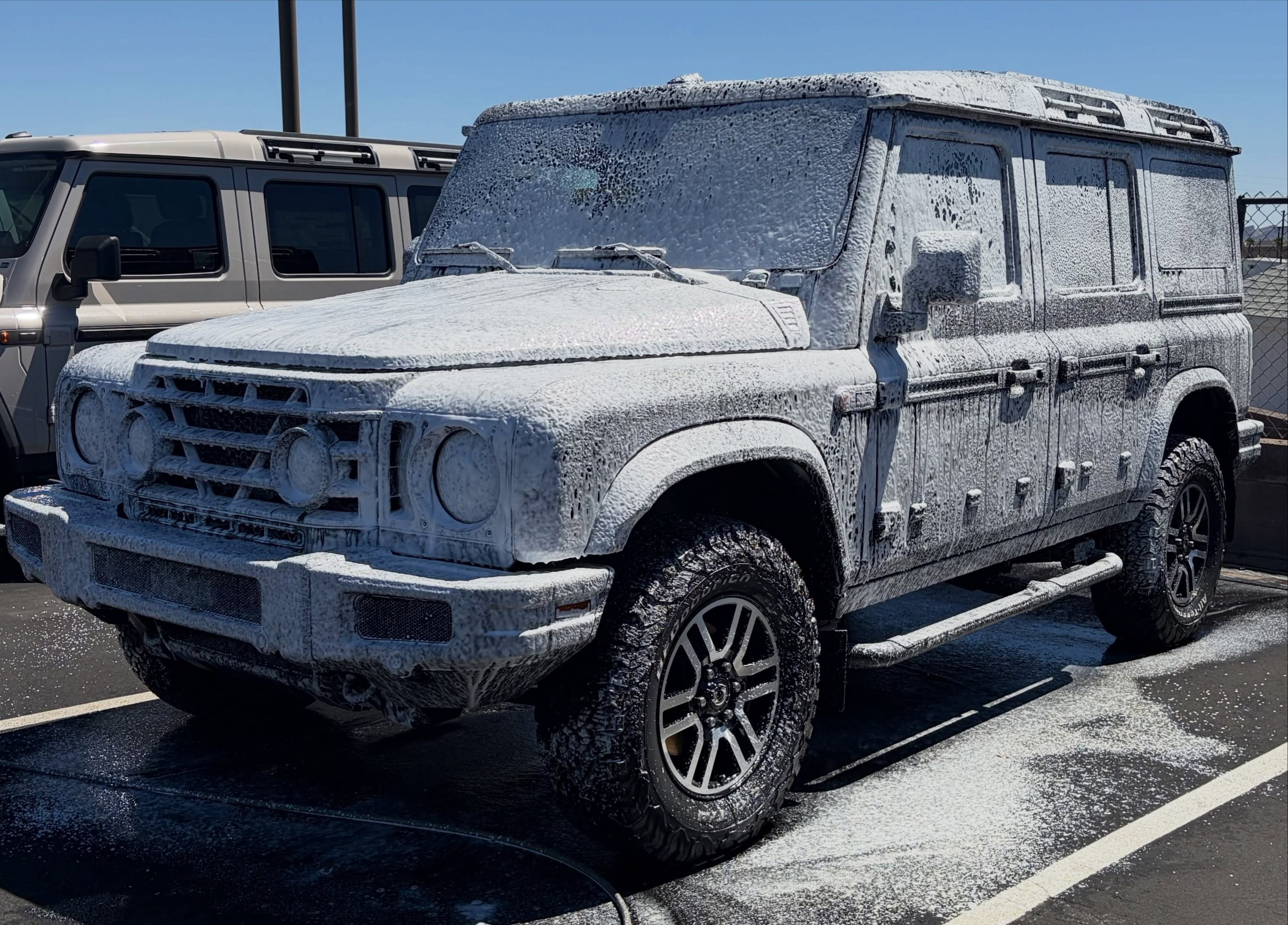 An SUV covered in thick white car wash soap foam